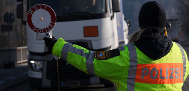 Auf dem Bild ist eine Polizistin zu sehen, die einen LKW anhält.